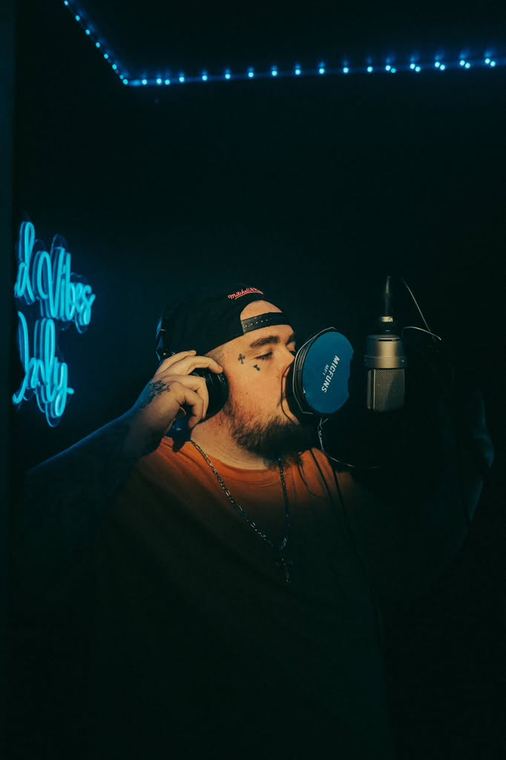 Recording at the mic beside a neon sign
