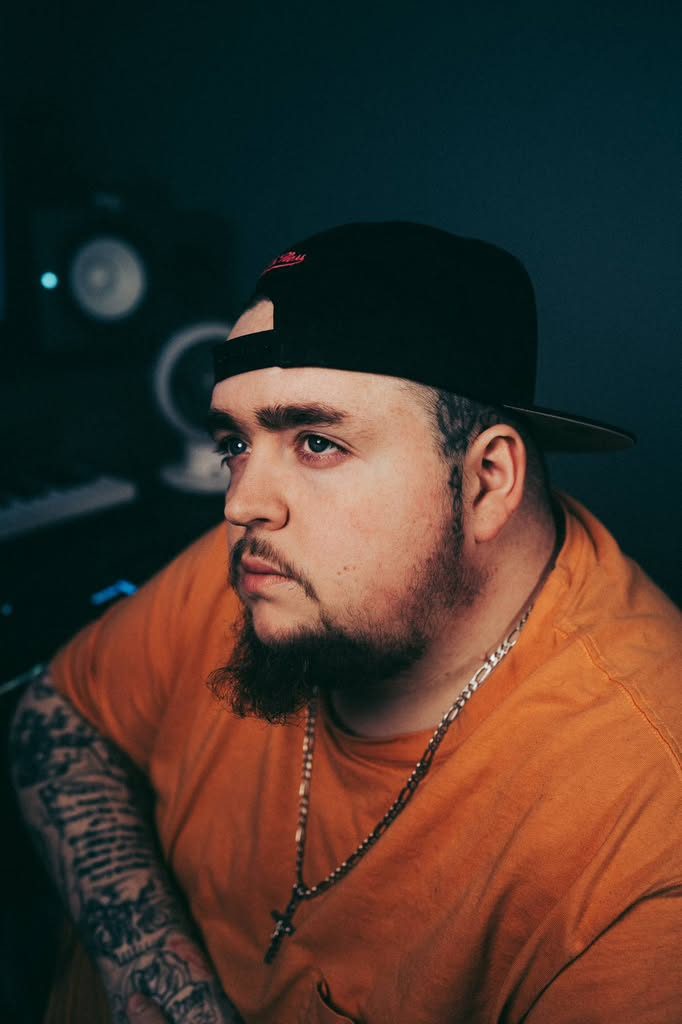 Studio portrait in an orange tee and backwards cap